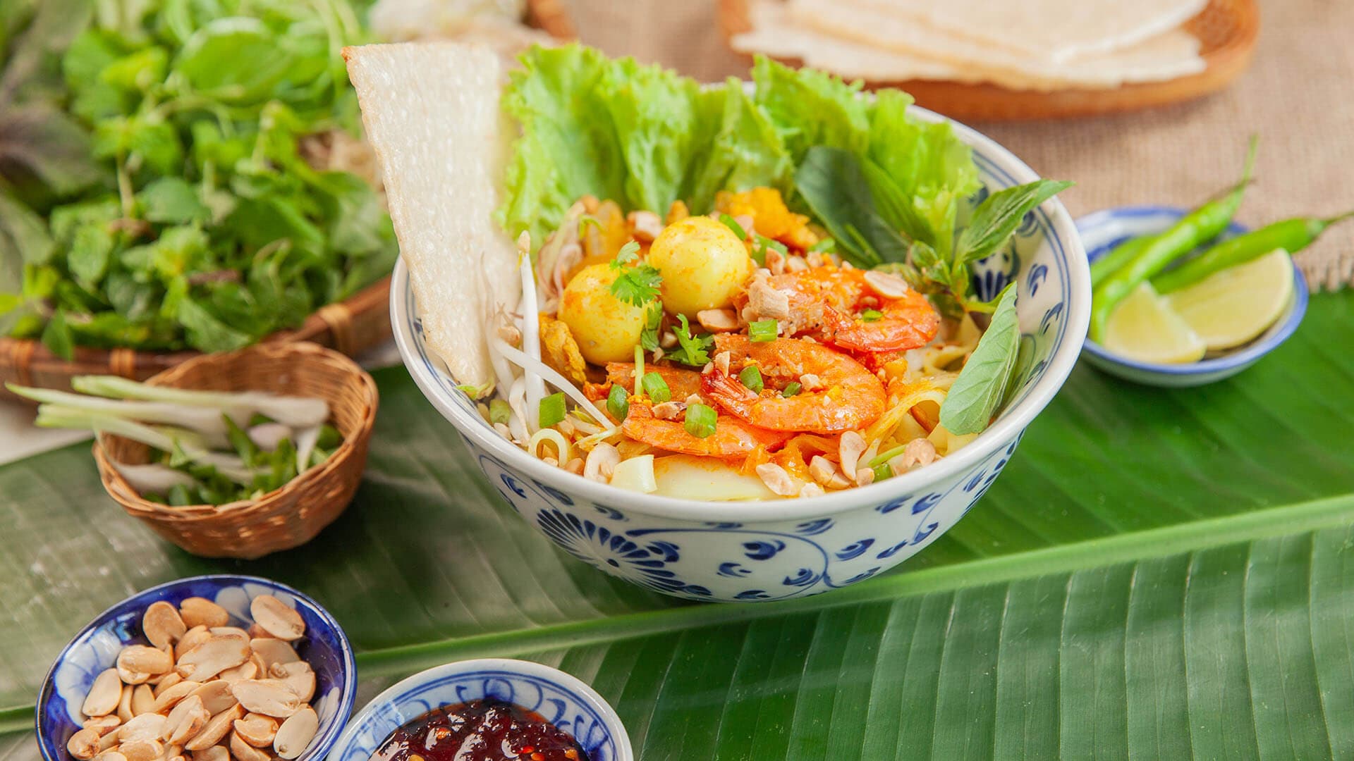Yellow turmeric noodles with shrimp and rice crackers on the side